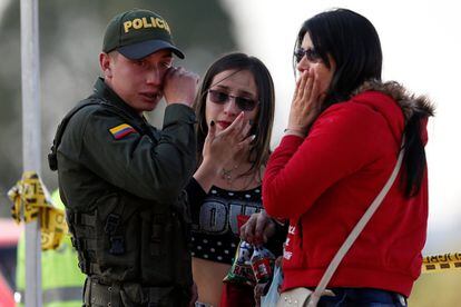 Un policía y dos mujeres lloran en el lugar donde ocurrió el atentado, en Bogotá. Mientras tanto, las fuerzas de seguridad tratan ahora de determinar qué grupo criminal tiene la capacidad y la estructura para perpetrar un atentado de estas características.