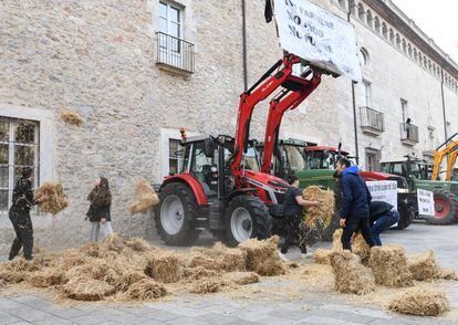 Agricultores protestan tirando paja ante la Delegación de la Generalitat en Girona, este martes.