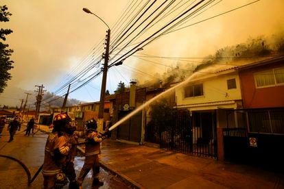 Una cuadrilla de bomberos rocía agua sobre los tejados de las viviendas de un barrio de Viña del Mar, el 3 de febrero de 2024. 