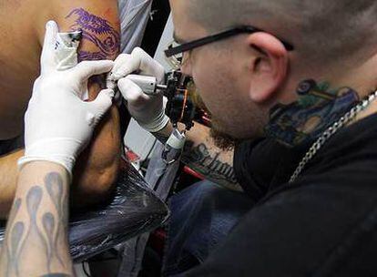 Un tatuador trabaja sobre el brazo de una persona.