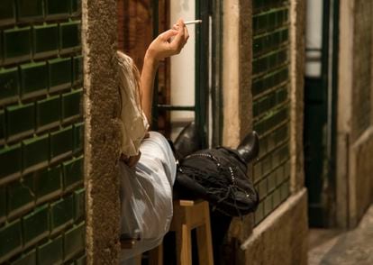 Una persona fumando un cigarro a las puertas de un bar en Lisboa, Portugal.