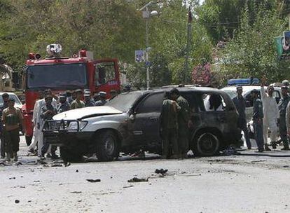 Varios transeúntes observan la escena del atentado con coche bomba que mató al número dos del espionaje afgano y a otras 22 personas en el municipio de Mehtar Lam.