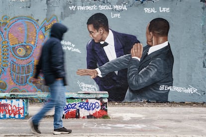 Berlin (Germany), 01/04/2022.- A passer-by walks past a graffiti mural showing a slap-in-the-face scene that took place at the 2022 Academy Awards ceremony, sprayed on a wall at Mauerpark public park in Berlin, Germany, 01 April 2022. The artwork by Dominican artist Jesus Cruz Artiles, aka Eme Freethinker, portrays US actor Will Smith slapping US comedian Chris Rock in the face during the incident at the Oscars over an assumed verbal insult of Smith's wife, US actress Jada Pinkett Smith. (Alemania) EFE/EPA/CLEMENS BILAN