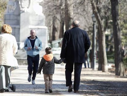 Unos abuelos pasean con su nieto por el parque.