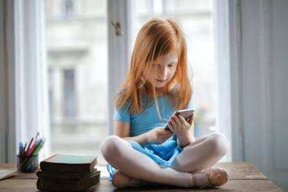 Una niña usa su teléfono móvil.