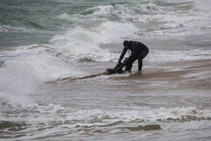 Un agente de la Guardia Civil rescata el cadáver de un inmigrante el pasado jueves en una playa de Caños de Meca en Cádiz.