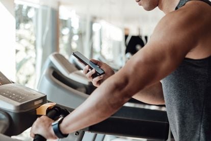 Una persona mira su teléfono móvil mientras utiliza una cinta de correr.