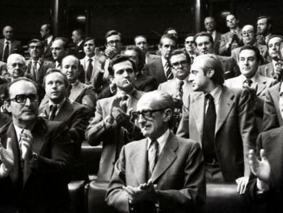 El presidente del Gobierno, Adolfo Suárez (a la derecha), y los vicepresidentes Enrique Fuentes Quintana (a la izquierda)y el teniente general Manuel Gutiérrez Mellado, aplauden en pie desde sus escaños, junto al resto de diputados, tras la aprobación de la Ley de Amnistía el 14 de octubre de 1977.