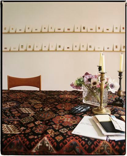 El comedor de diario, un salón que también sirve de despacho y el dormitorio. En la pared del comedor, 'Stamps with Paintings', (2005), de Hans-Peter Feldmann; sobre la mesa, una alfombra persa del siglo XIX y candelabros de bronce comprados en el Rastro. Las flores son de Fransen et Lafite. 