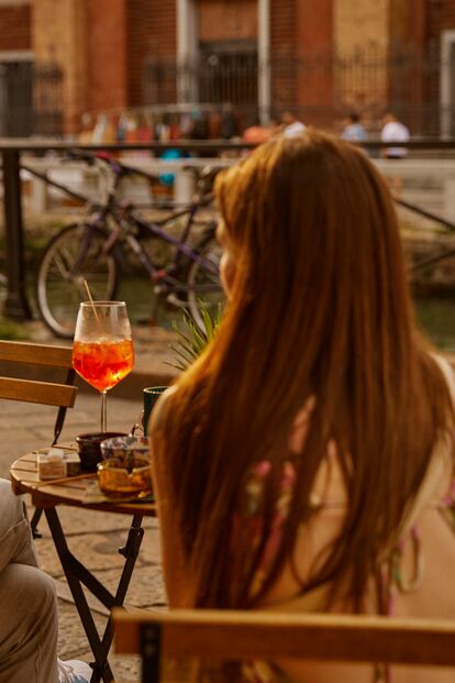 Una mujer disfruta de un Spritz en los Navigli de Milán.