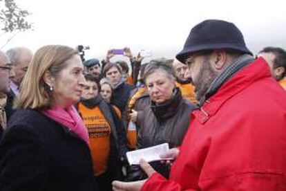 La ministra de Fomento, Ana Pastor (i), escucha a Benito Alonso, representante de los emigrantes retornados, durante el acto de inauguración de las obras de rehabilitación del Castillo de Santa Cruz en A Guarda, en el que decenas de personas han recibido a la ministra al grito de "no somos defraudadores" y han conversado con ella para trasladarle sus solicitudes.