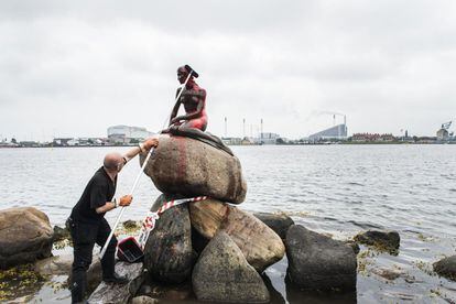 Un empleado municipal limpia la Sirenita en Copenhague, Dinamarca. La escultura, la mayor atracción turística de Dinamarca, apareció hoy pintada de rojo en protesta por la caza de ballenas en las Islas Feroe, territorio autónomo del reino danés.