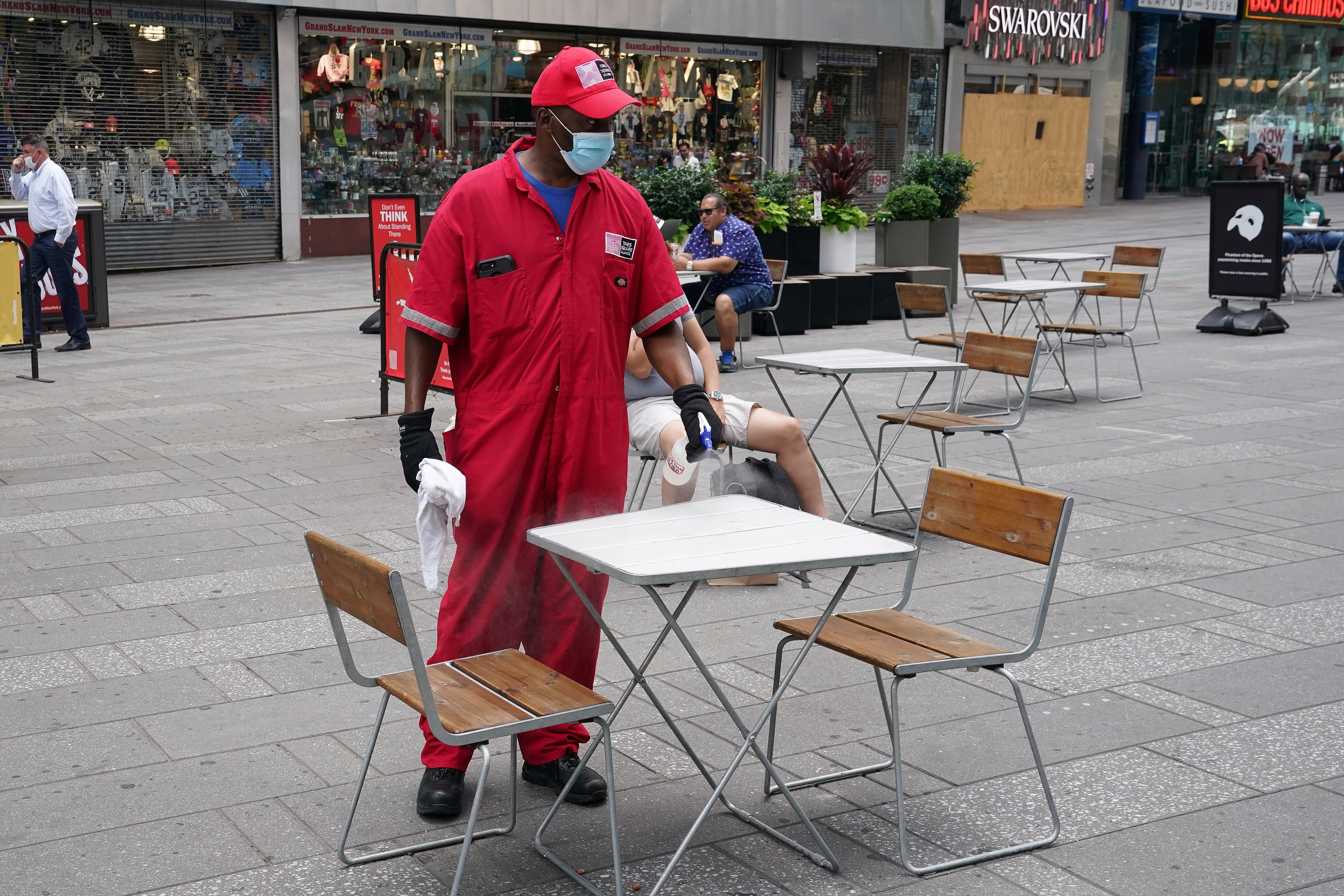 Un operario limpia una mesa de una terraza casi vacía en Times Square a finales de junio.