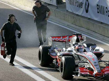 Un asistente corre con el extintor hacia el coche de Fernando Alonso.