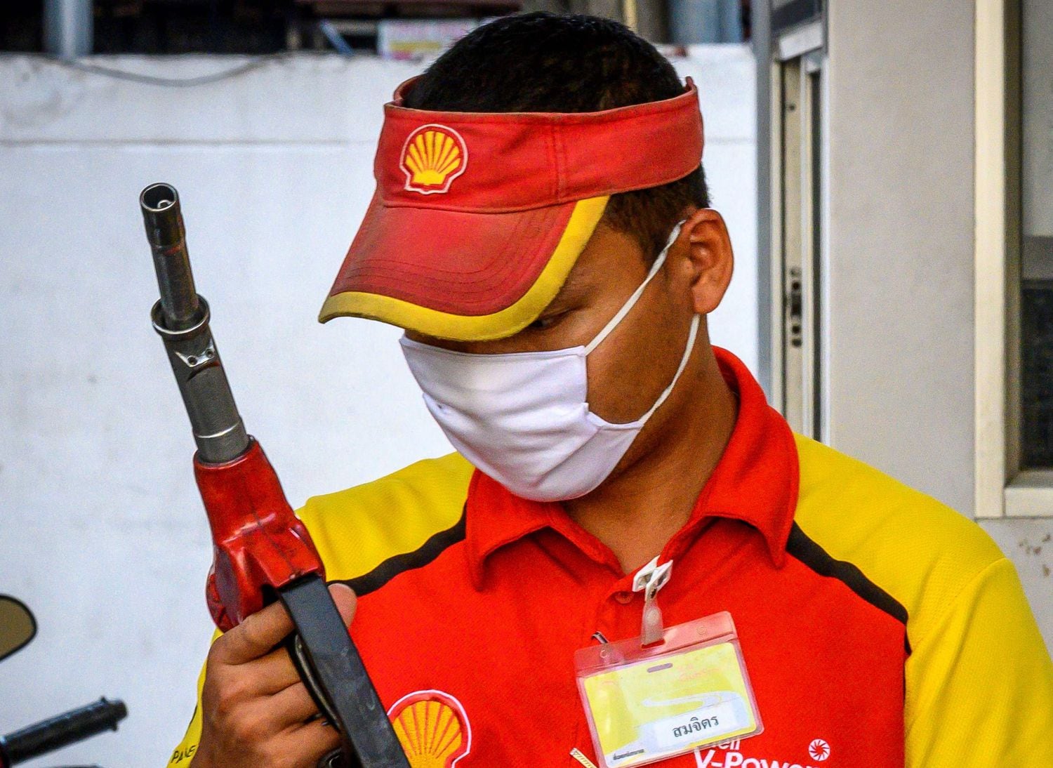 Un empleado de una gasolinera Shell en Bangkok, pertrechado con una mascarilla para protegerse del coronavirus.