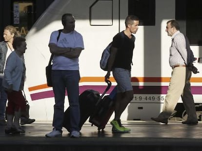 Varios pasajeros de tren con equipajes caminan por un and&eacute;n de la estaci&oacute;n de Chamart&iacute;n, en Madrid.  