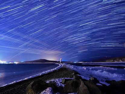 Lluvia de estrellas de las Gemínidas durante su pico, en el cielo nocturno sobre el faro de Tokarevsky en el cabo de Egersheld en la isla de Russky en el mar de Japón.