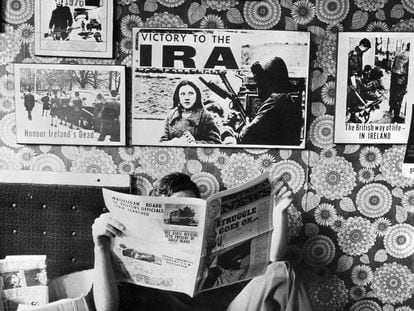 Un activista del IRA lee periódicos en su oficina en 1976 bajo una pared cubierta con carteles de propaganda de la organización terrorista.