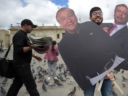 Un hombre posa sosteniendo carteles de cartón con imágenes de los candidatos a la Presidencia en Colombia en Bogotá.