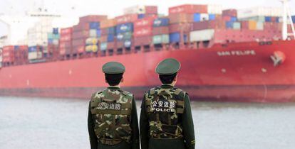 Dos policías esperan la llegada de un buque de carga en el puerto de Qingdao, China.