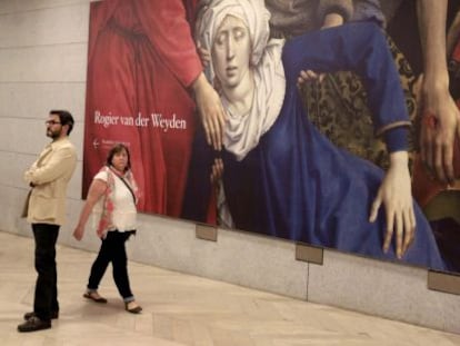 Dos espectadores junto al 'Descendimiento de la cruz' del flamenco Rogier van der Weyden, en el museo de El Prado.