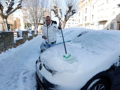 Una persona retira la nieve de un coche en una calle de Soria, este sábado.