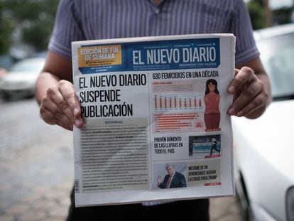 Un hombre muestra la primera plana de 'El Nuevo Diario' que anuncia la decisión del periódico de echar el cierre.