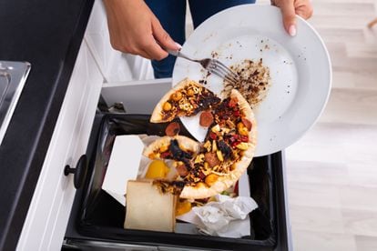 Una persona tira restos de comida a la basura en un domicilio.