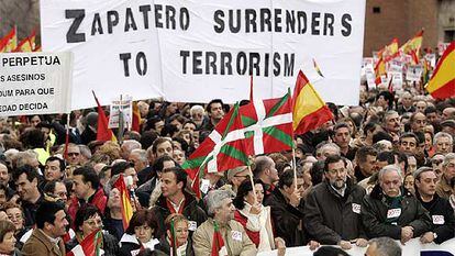 Mariano Rajoy porta la segunda pancarta. Detrás, en inglés, se lee "Zapatero se rinde al terrorismo".
