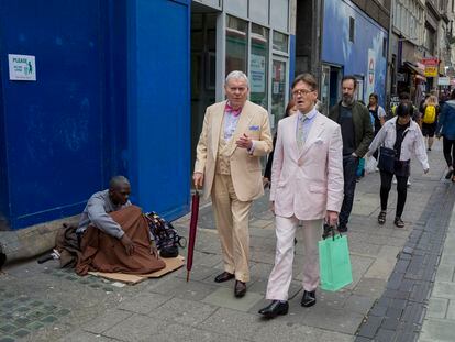 Un sintecho y dos hombres bien vestidos en la calle Oxford, en Londres.