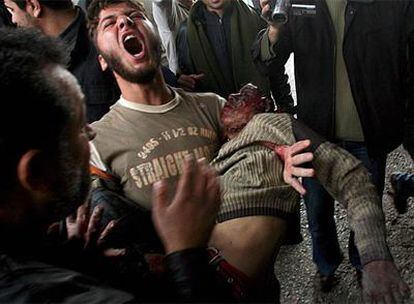 Un hombre lleva en sus brazos el cuerpo de un joven palestino muerto en el bombardeo de ayer en Gaza.