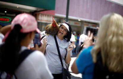 Una turista posa para una fotografía con el gallo Paquito.