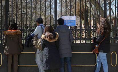 Un grupo de personas frente al Retiro, donde un cartel alude al cierre del parque después de que falleciese un niño de 4 años tras caerle un árbol encima.