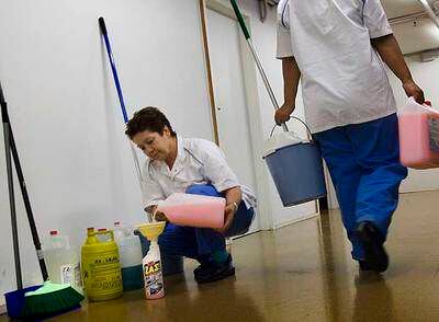 Dos empleadas manejan productos químicos de limpieza en el lugar de trabajo.
