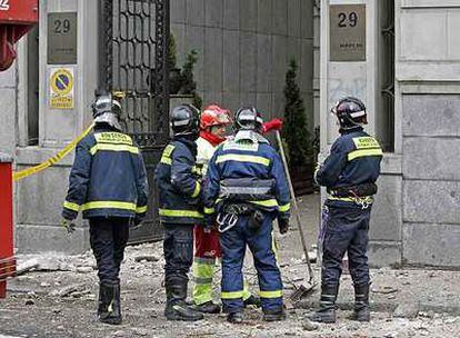 Los bomberos revisan el lugar en el que un escudo desprendido de una cornisa acabó con la vida de una mujer en el paseo de Recoletos.