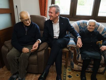 El presidente gallego, Alfonso Rueda, visita el pasado 5 de diciembre en su casa de Rois (A Coruña) a dos beneficiarios del nuevo bono para dependientes, en una imagen divulgada por la Xunta.