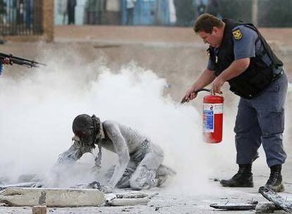 Un policía salva a un hombre quemado vivo por una turba en un suburbio de Johanesburgo.