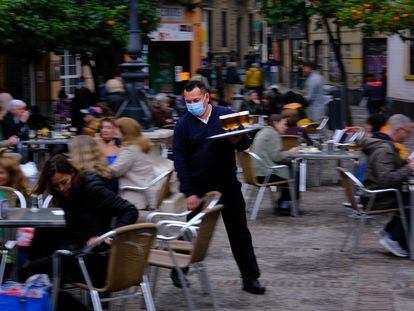 Un camarero sirve una mesa en una terraza de Sevilla.