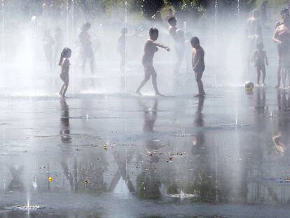 Unos niños juegan con el agua en una de las fuentes de Madrid Río.