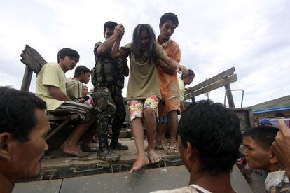 Varias personas que fueron rescatadas  de sus casas  inundadas son ayudadas por los militares en New Bataan, provincia del Valle de Compostela, al sur de Filipinas. 