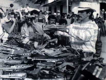 Carlos Pizarro, líder del M-19, envuelve su pistola en una bandera colombiana en el acto de entrega de armas del grupo guerrillero, en marzo de 1990.