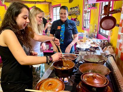 La chef Alejandra Treviño supervisa la preparación del menú con dos visitantes, en su escuela de Puerto Morelos (México).
