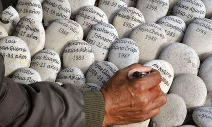 Un hombre escribe en un memorial a las v&iacute;ctimas en Per&uacute;.