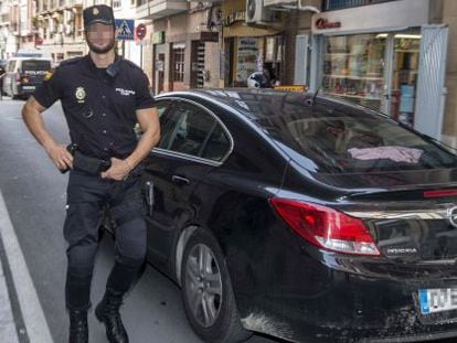 Un membre de la Policia Nacional custodia el vehicle que trasllada dos dels sis policies detinguts a Cartagena.