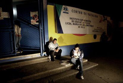 Dos empleados de las elecciones esperan a las puertas de un centro de votación en Ciudad de Guatemala.