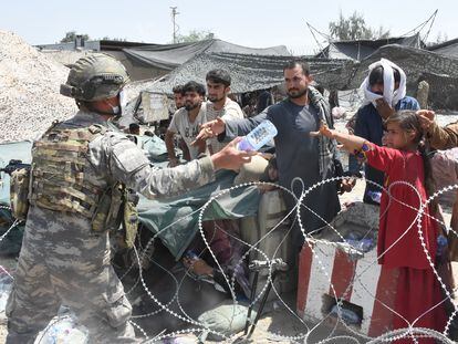 Soldados reparten agua a afganos acampados junto al aeropuerto de Kabul.