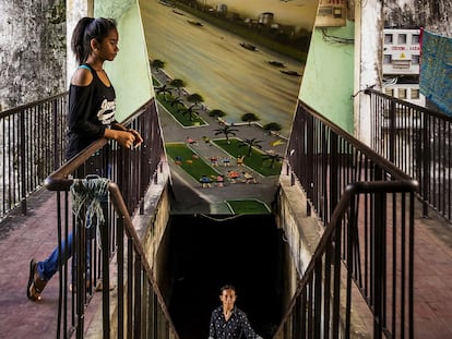 Existe un edificio blanco que se cae pedazos, decrépito y situado en pleno centro de una Phnom Penh -la capital de Camboya- en rápido cambio. Parece ajeno a los rascacielos de vidrio y acero que brotan a su alrededor. Pero la pujante comunidad formada por más de 2.500 artistas, monjas, trabajadoras del sexo y empleados públicos que vive en este enorme asentamiento marginal saben muy bien que lo que para ellos es su hogar tiene las horas contadas. En la imagen, un mural en la escalera con una representación de Phnom Penh y el río Mekong.