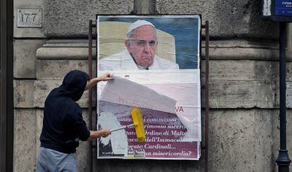 Un operario cubre un cartel contra el Papa en una calle de Roma.