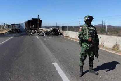 Un soldado del Ejército mexicano hace guardia ante los restos de un vehículo quemado, que miembros del crimen organizado usaron para crear una barricada sobre la carretera, en Mazatlán (Sinaloa), a 200km de la capital estatal, Culiacán.