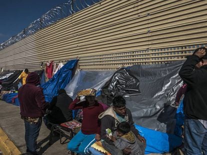 Un grupo de migrantes aguarda en un campamento improvisado frente al muro fronterizo en San Luis Río Colorado, en Sonora.